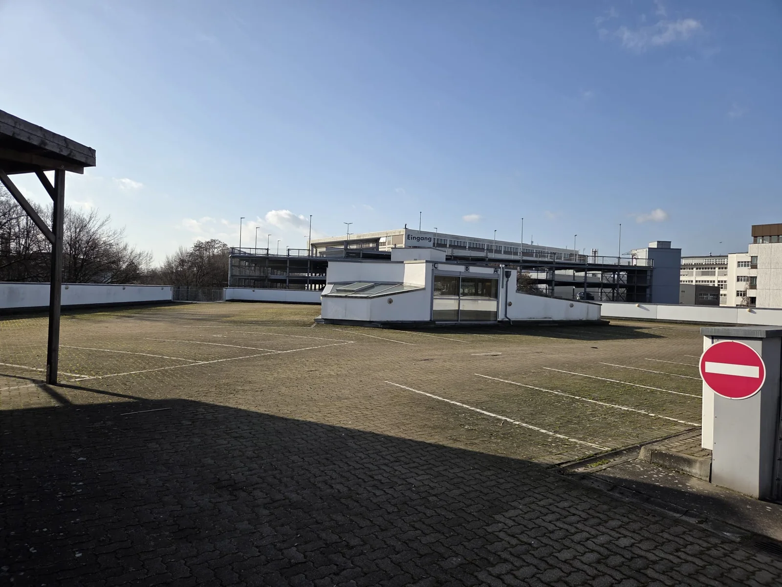 Originalaufnahme der gepflasterten Parkfläche mit Gebäuden im Hintergrund